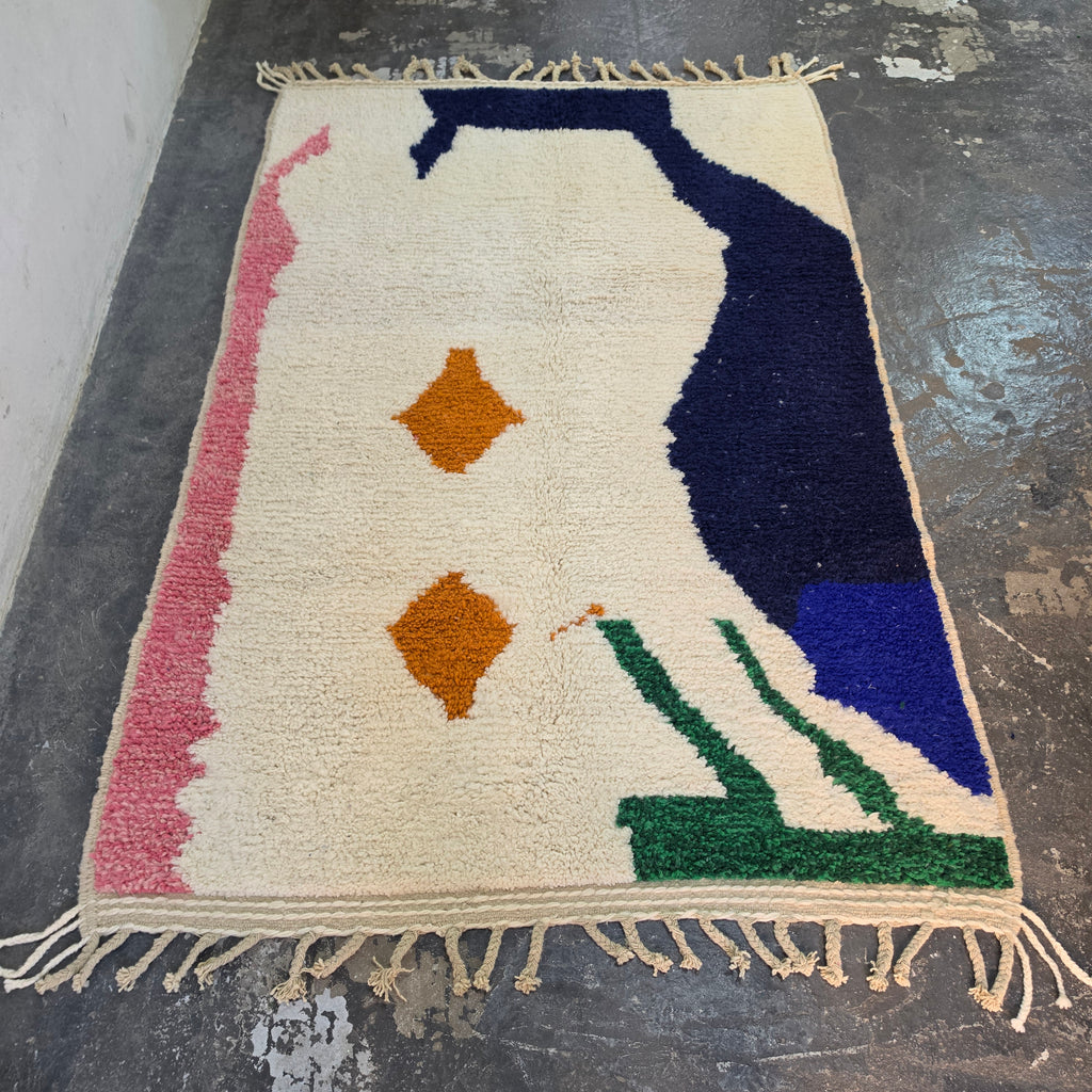 Abstract Azilal rug laid flat, full top-down view of cream wool with navy, pink, green and orange shapes