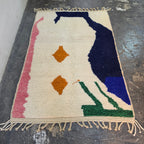 Abstract Azilal rug laid flat, full top-down view of cream wool with navy, pink, green and orange shapes