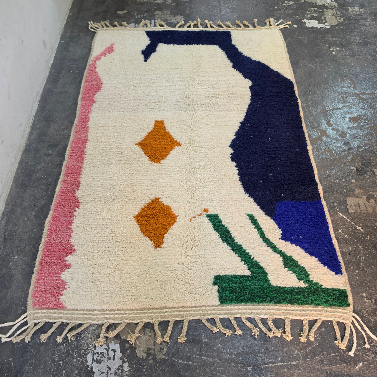 Abstract Azilal rug laid flat, full top-down view of cream wool with navy, pink, green and orange shapes