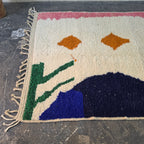 Angled view of the abstract Azilal rug showing navy and royal blue shapes, green lines and fringe