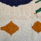 Close-up of burnt orange diamonds and green lines in cream wool