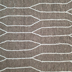 Close-up of ivory elongated hexagon lines woven into taupe wool