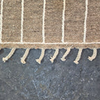 Close-up of the hand-finished tassels along the edge of the taupe kilim