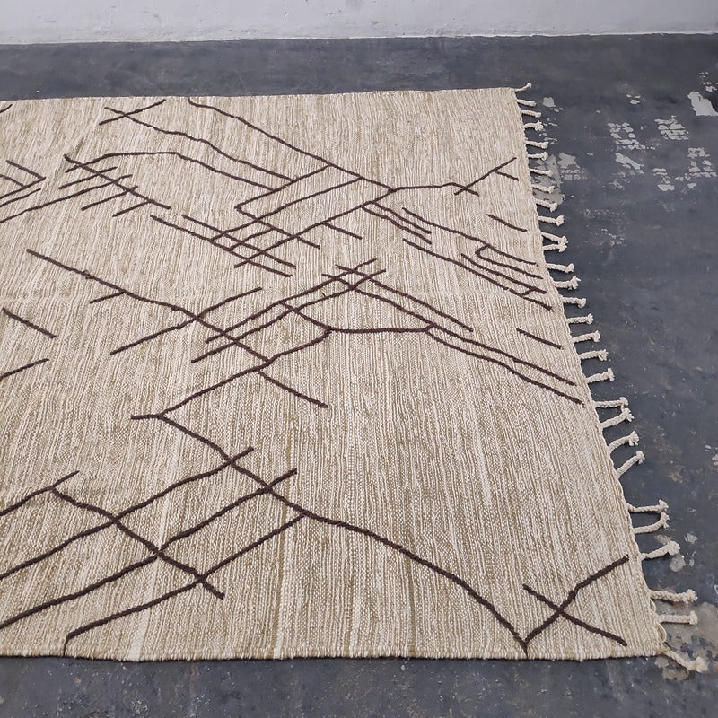 Moroccan Kilim rug laid flat with visible fringe tassels on natural beige wool