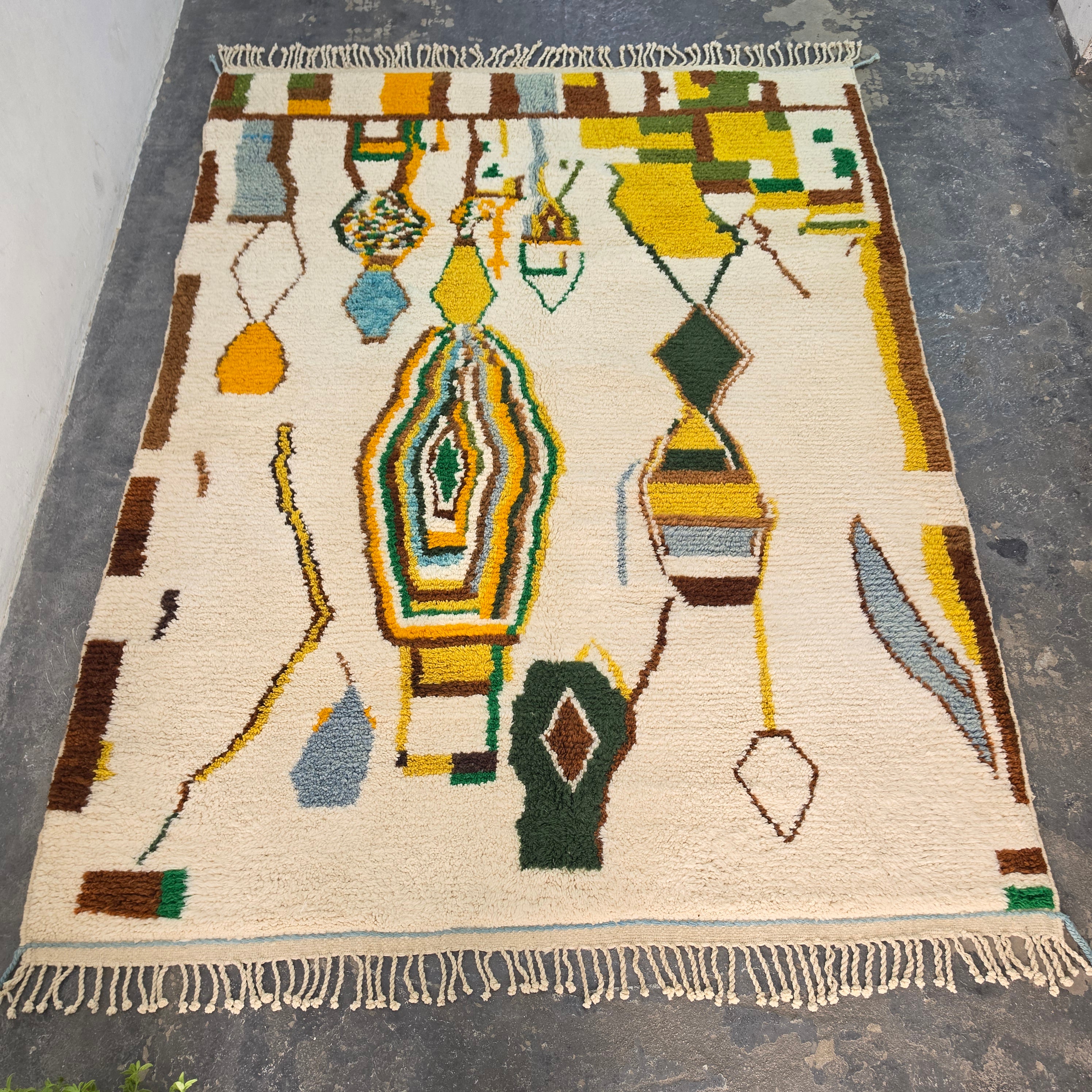 Moroccan Boujad rug laid flat, full top-down view of abstract tribal pattern in mustard, green, brown, and blue wool