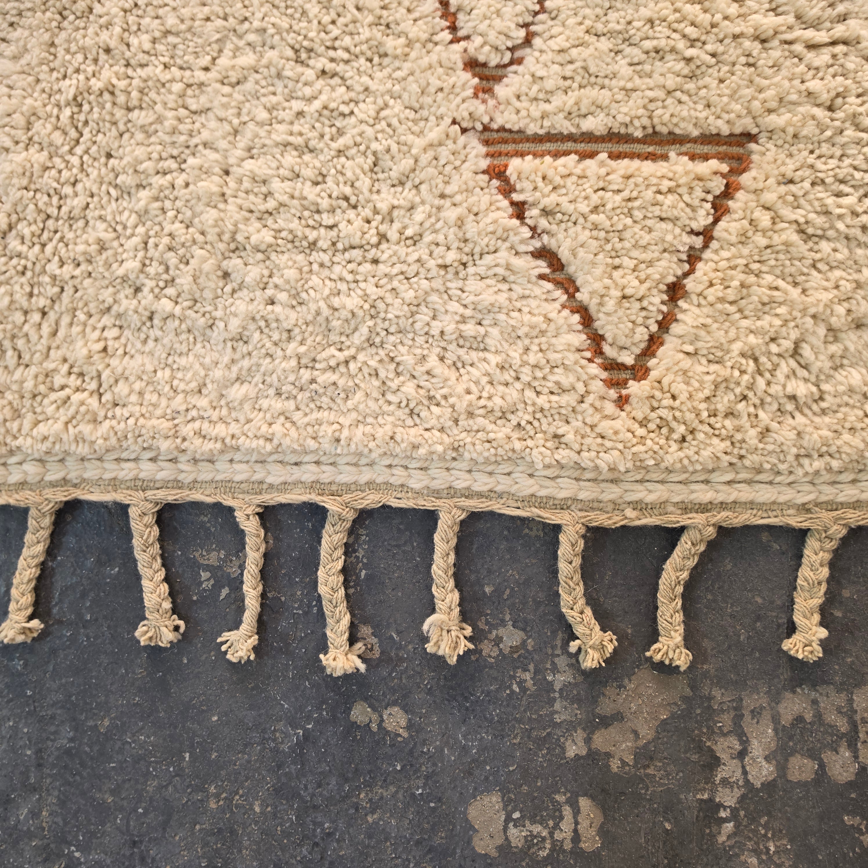 Close-up of hand-tied fringe and rust triangle motif on a Moroccan Berber rug