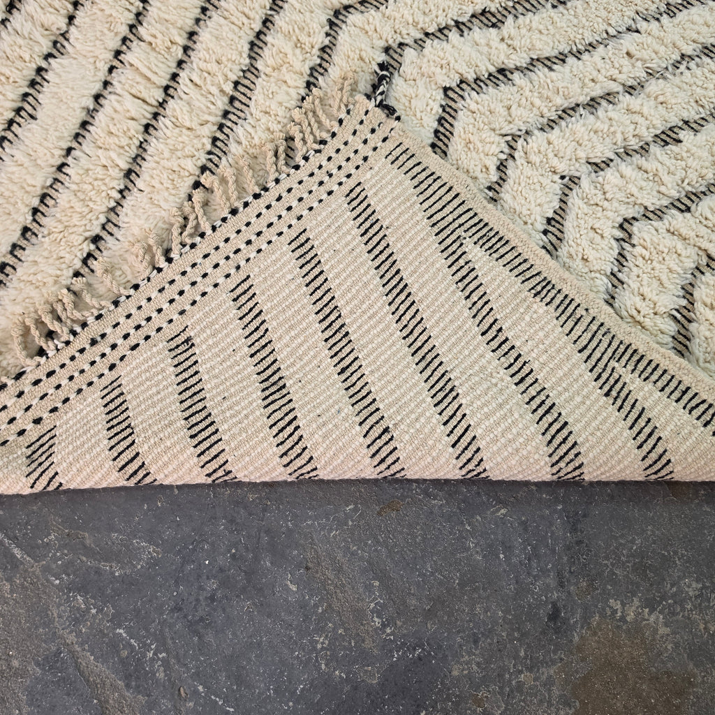 Folded corner of Moroccan Beni Ourain rug showing the woven cotton backing on the reverse side