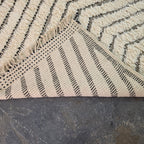 Folded corner of Moroccan Beni Ourain rug showing the woven cotton backing on the reverse side