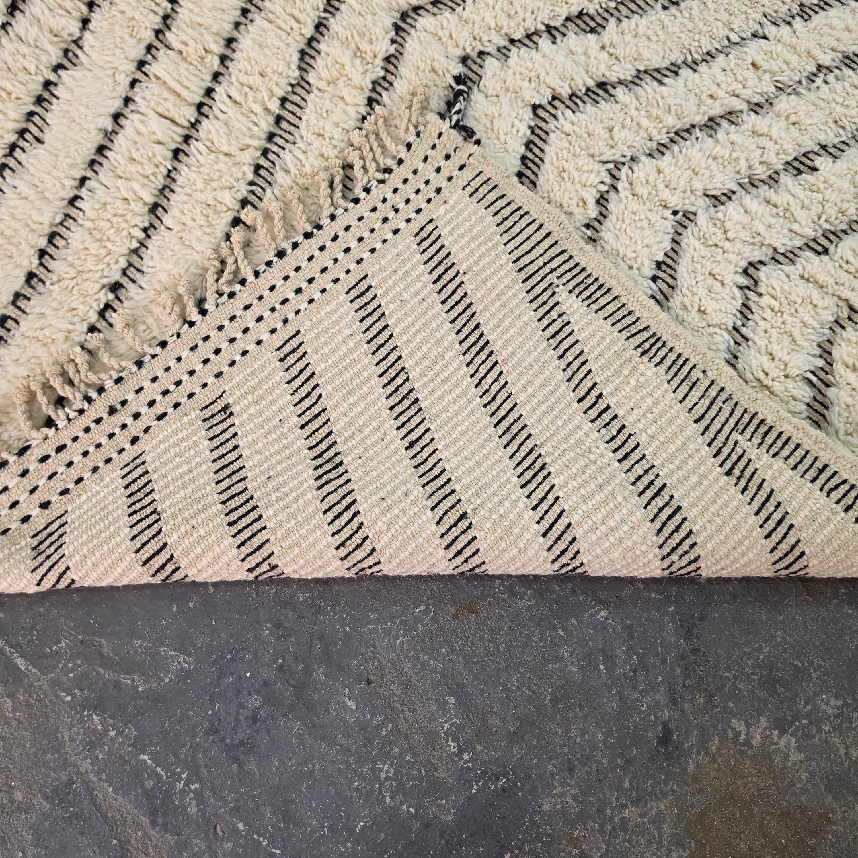 Folded corner of Moroccan Beni Ourain rug showing the woven cotton backing on the reverse side