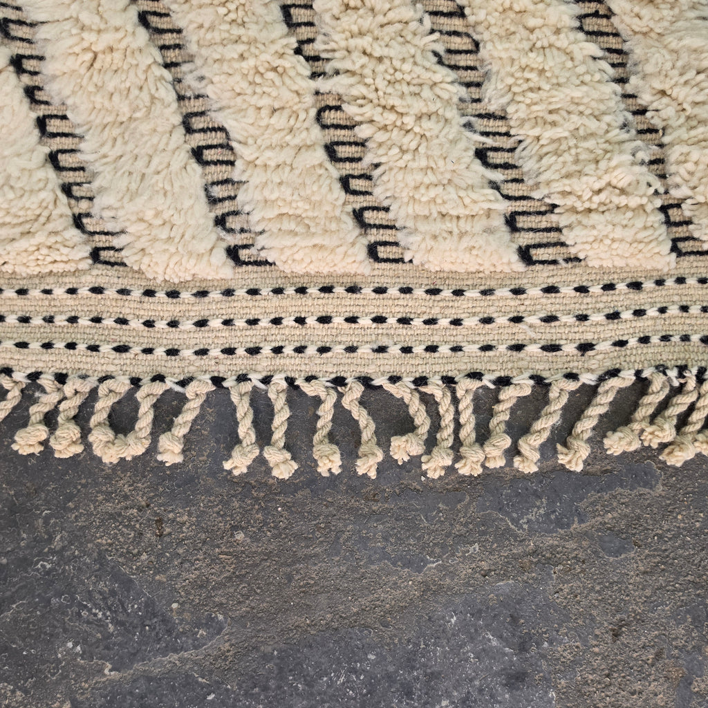 Close-up of hand-tied fringe tassels and chevron pattern on a Moroccan Beni Ourain rug