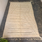 Modern boho Moroccan rug laid flat, full top-down view of ivory wool with carved lines