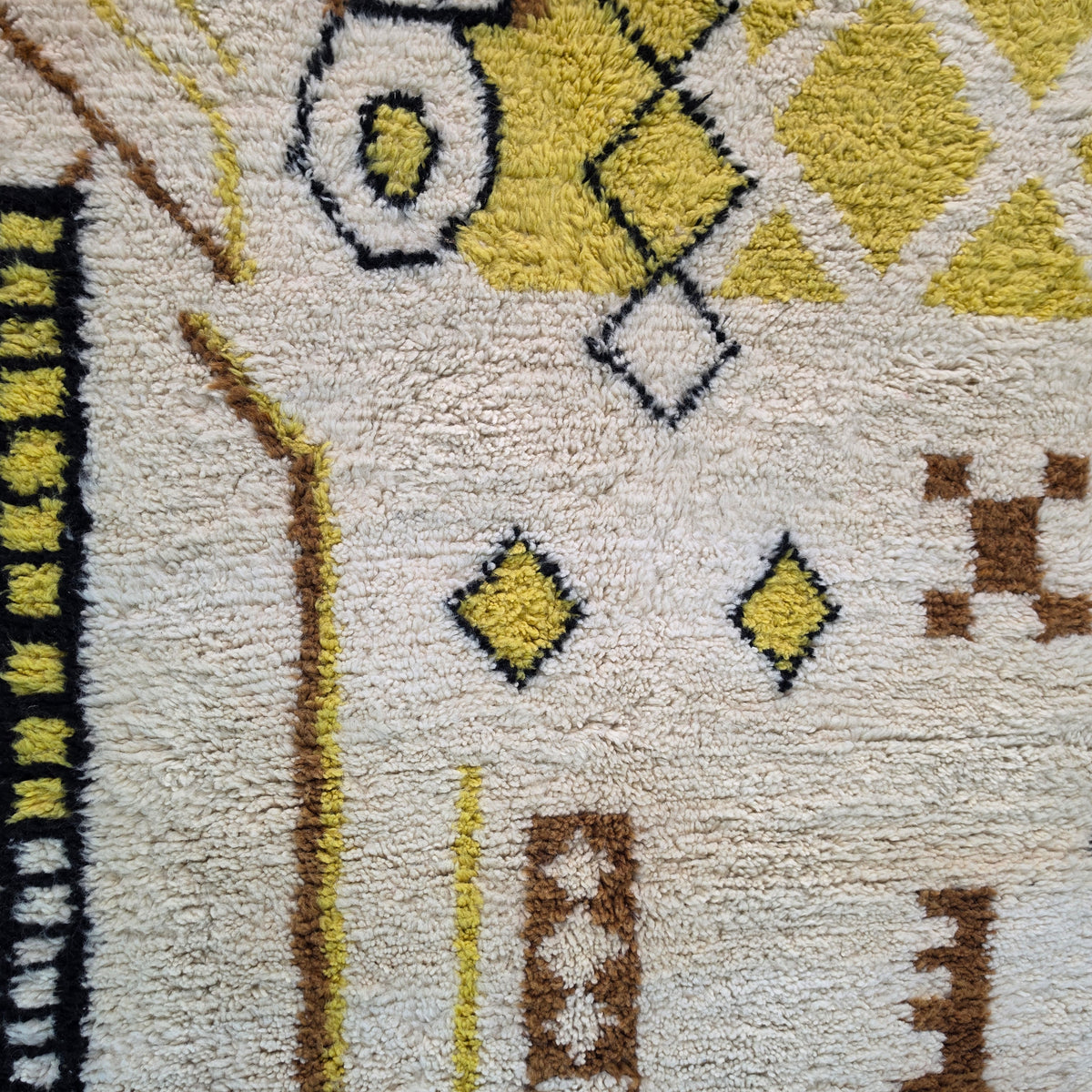 Macro close-up of yellow diamond and circle motifs on ivory Moroccan Berber wool