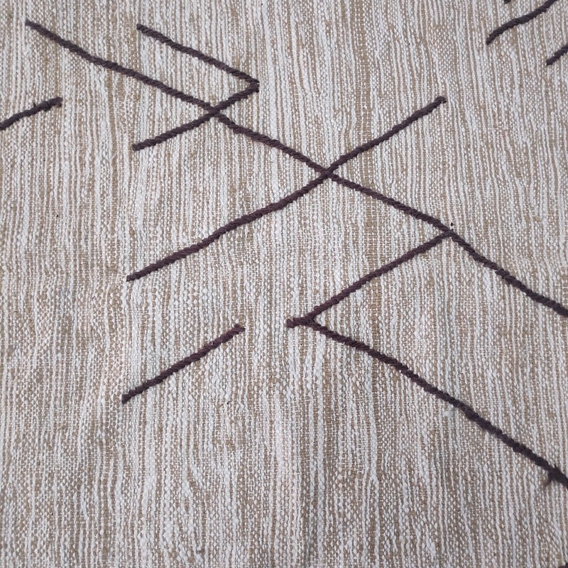 Close-up of the geometric line pattern hand-woven into natural beige wool