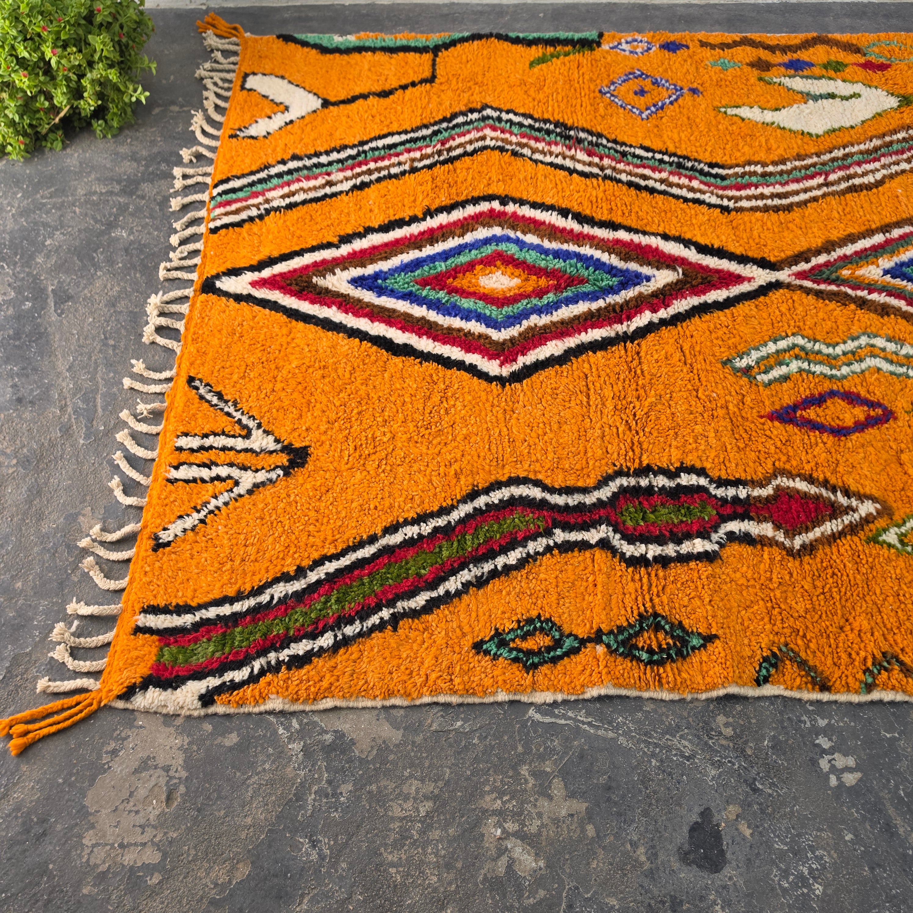Close angled view of orange Moroccan Boujad rug corner with diamond and arrow motifs