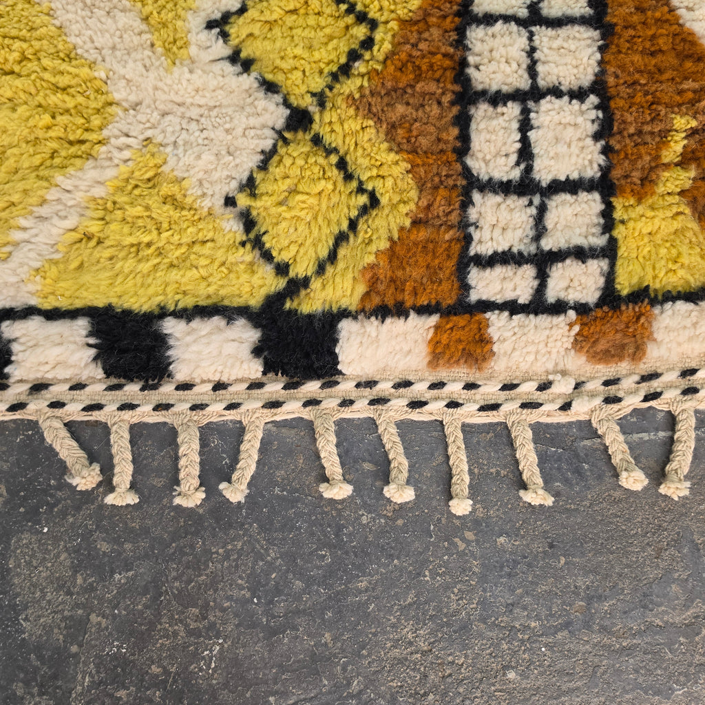 Close-up of yellow diamond pattern and checkerboard border on a Moroccan Berber rug