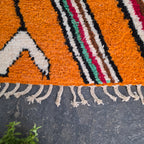 Close-up of striped border and fringe on an orange Moroccan Boujad wool rug