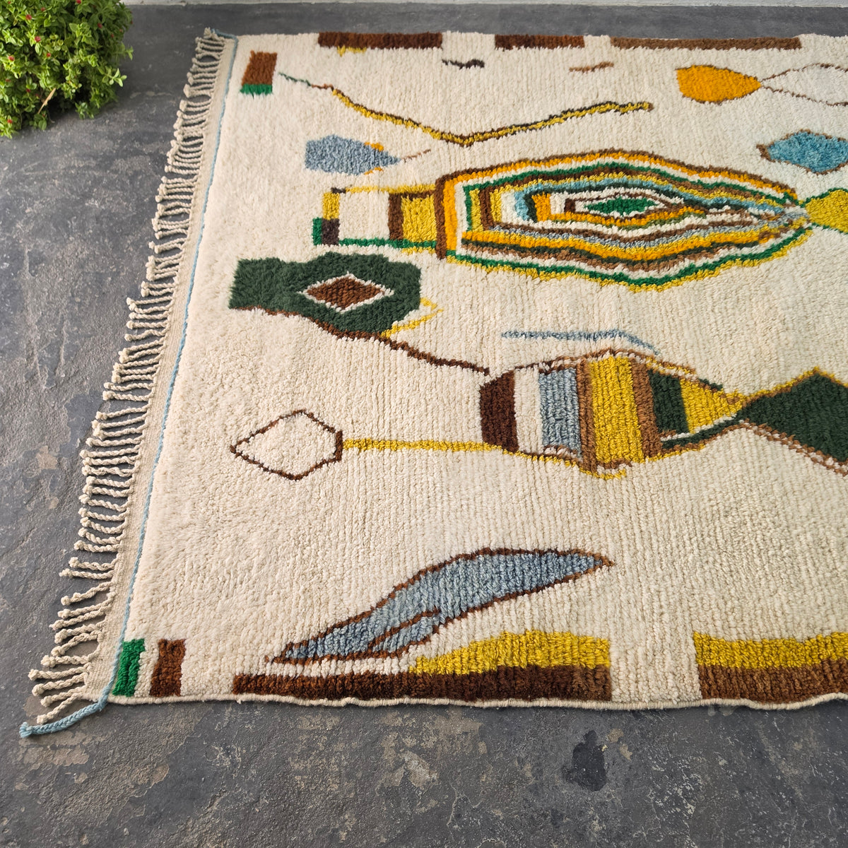 Angled view of colorful Moroccan Boujad rug showing concentric diamond motif and fringed edge