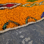 Close-up of vibrant orange wool pile texture on a Moroccan Boujad rug corner