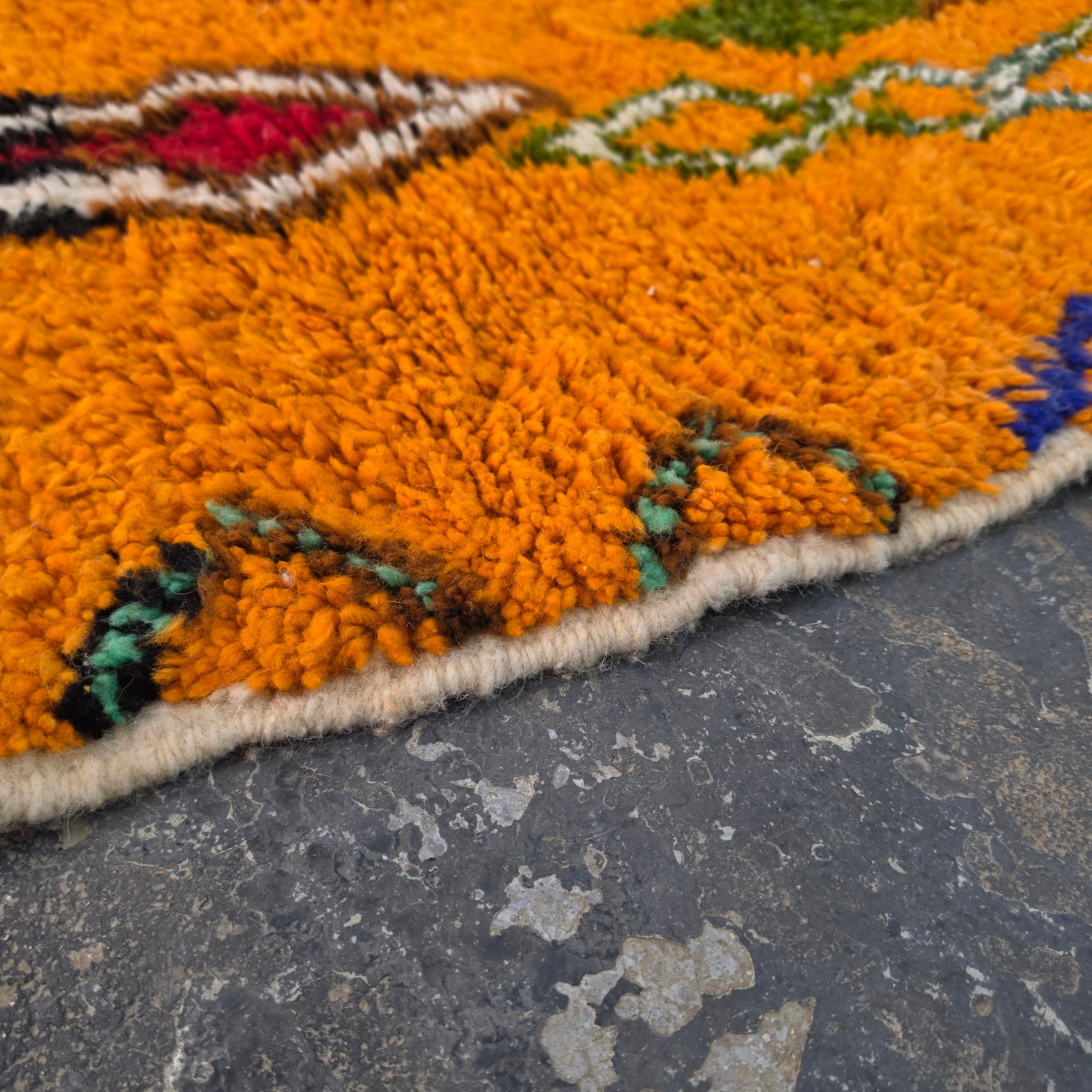 Close-up of vibrant orange wool pile texture on a Moroccan Boujad rug corner