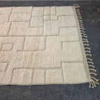 Angled view of the all-ivory Beni Ourain rug from the other side, with carved relief