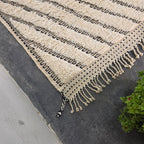 Close-up of Moroccan Beni Ourain rug corner showing fringe tassels and chevron edge pattern