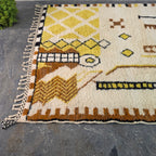 Angled view of Moroccan Berber rug corner showing yellow diamond trellis pattern and fringe