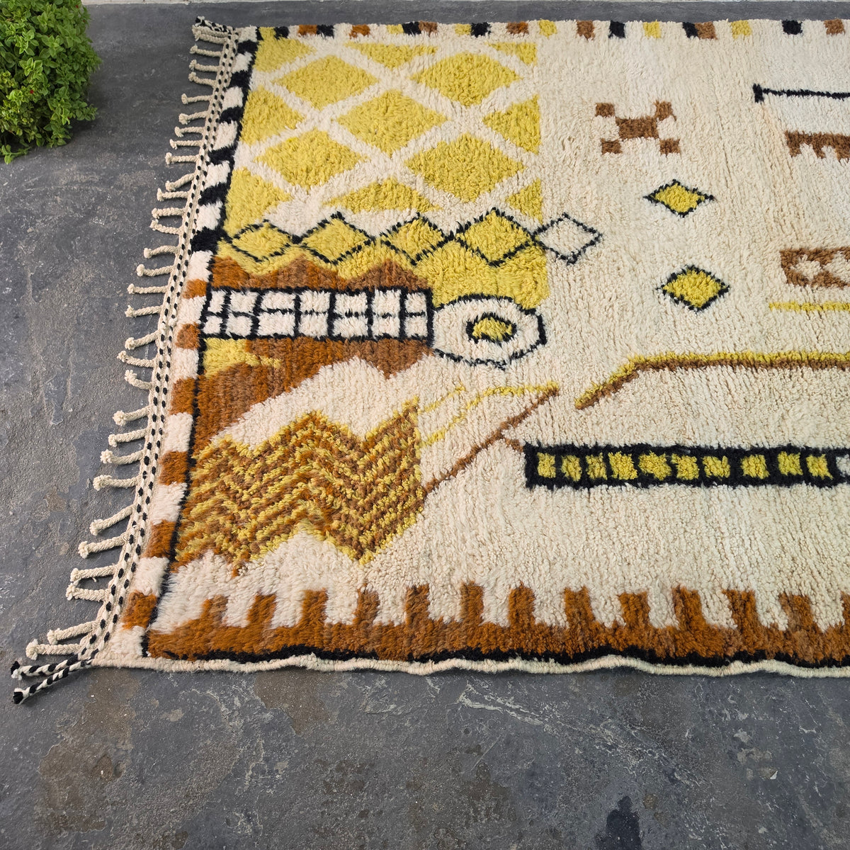 Angled view of Moroccan Berber rug corner showing yellow diamond trellis pattern and fringe