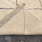 Folded corner of the Beni Ourain rug showing the woven reverse side and dotted border