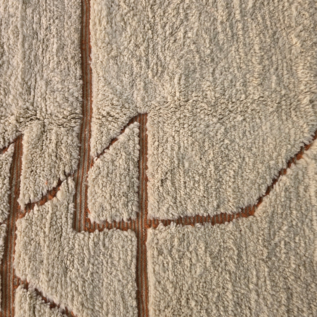 Macro close-up of rust-colored geometric pattern woven into cream wool pile
