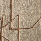 Macro close-up of rust-colored geometric pattern woven into cream wool pile