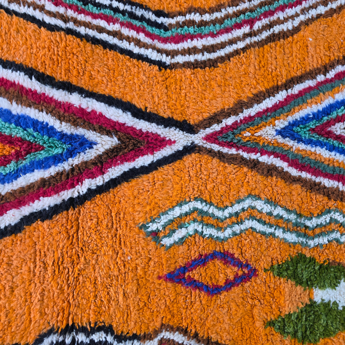 Macro close-up of colorful chevron and diamond motif on orange wool