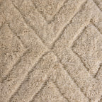 Close-up of the carved X relief in the thick ivory wool pile