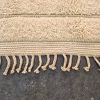 Close-up of the woven edge and hand-tied fringe of the ivory modern boho rug