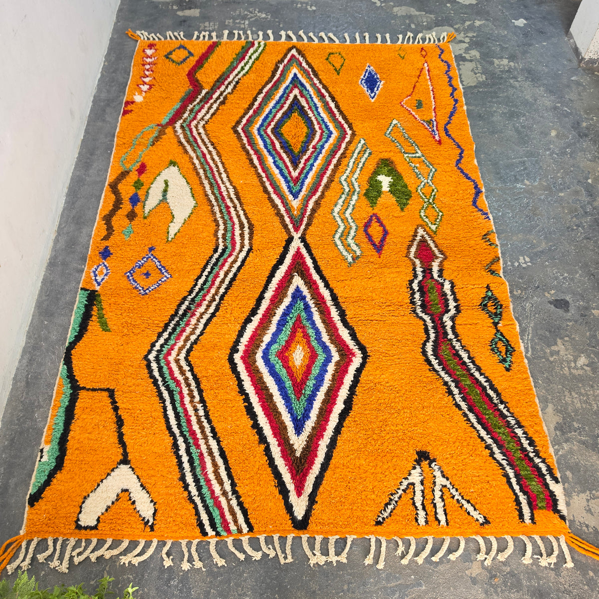 Vibrant orange Moroccan Boujad rug laid flat, full top-down view of colorful diamond pattern