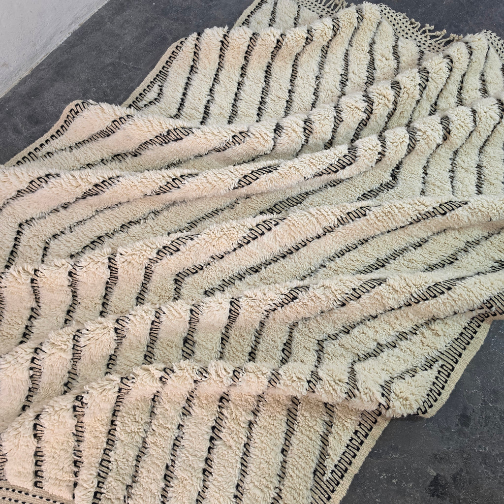 Moroccan Beni Ourain rug folded in soft waves showing the wavy chevron pattern