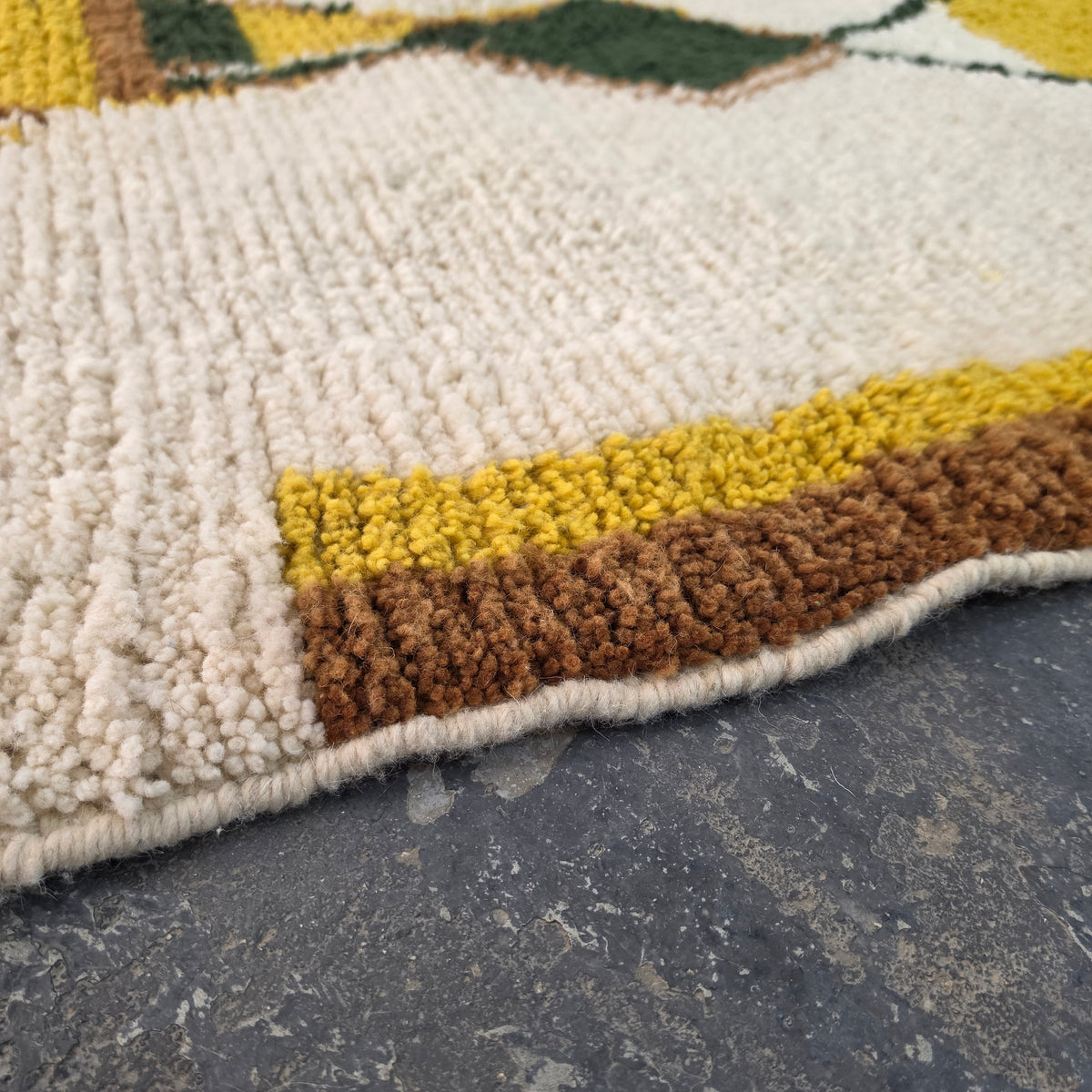 Close-up of mustard and brown wool pile texture on a Moroccan Boujad rug corner