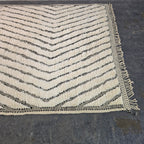 Close angled view of Moroccan Beni Ourain rug corner with chevron pattern and hand-tied fringe