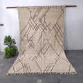 Handmade Moroccan Kilim wool rug hanging on display, showing full minimalist geometric line pattern in neutral beige