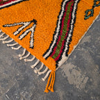 Close-up of orange Moroccan Boujad rug corner with arrow motif and hand-tied fringe