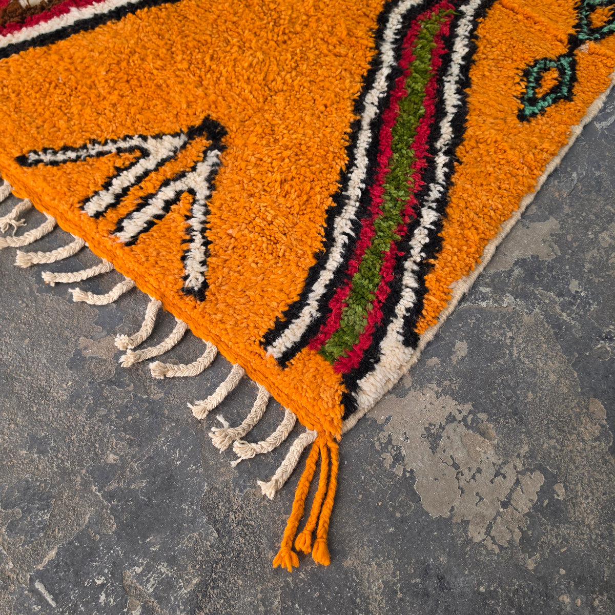 Close-up of orange Moroccan Boujad rug corner with arrow motif and hand-tied fringe