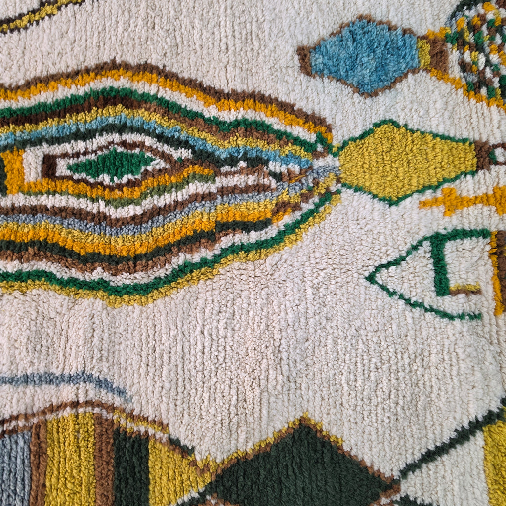Macro close-up of concentric diamond motif in mustard, green, and blue wool