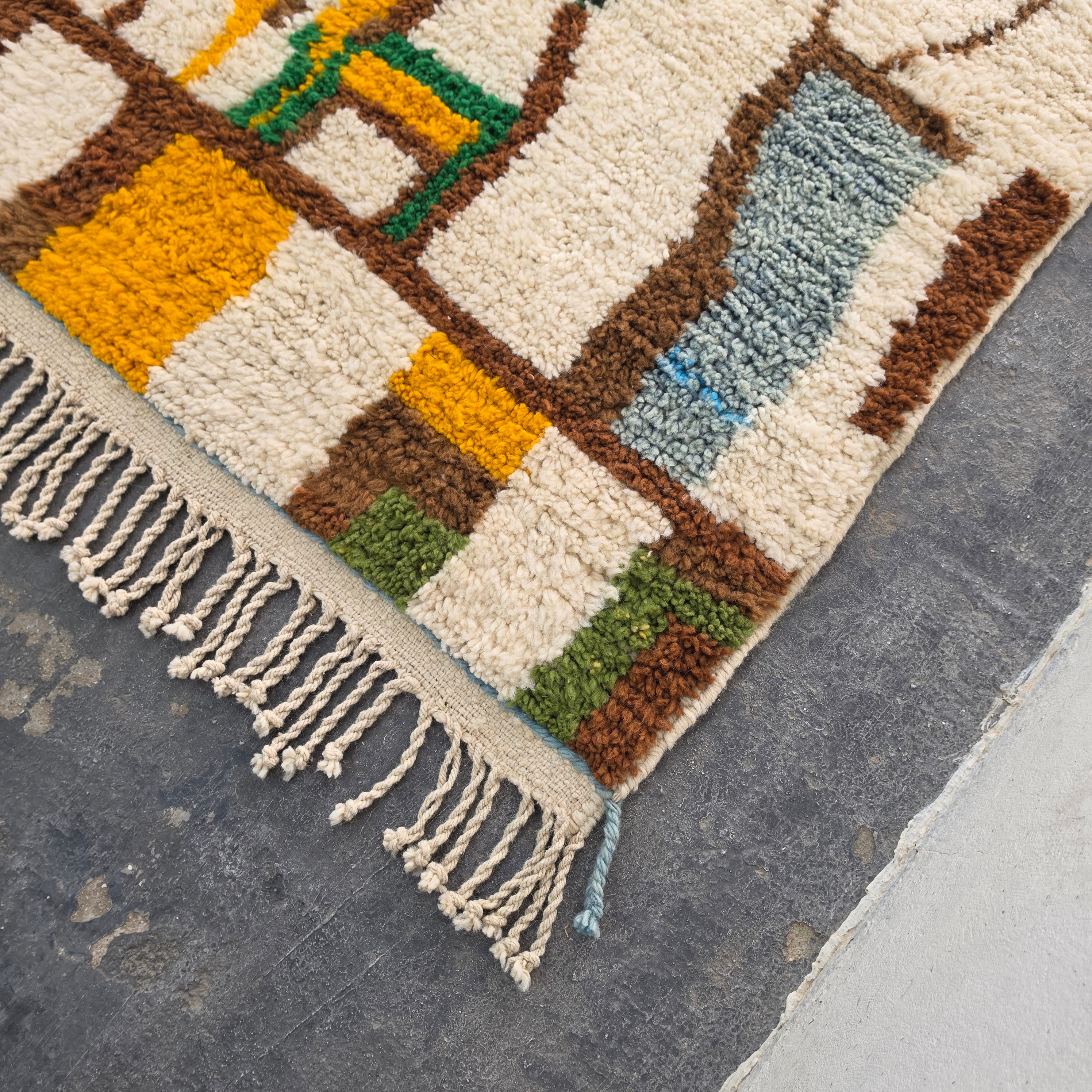 Close-up corner of Moroccan Boujad rug showing mustard, green, and brown wool tufting