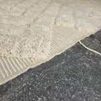 Close-up of the ivory wool pile and woven edge of the oversized Beni Ourain rug